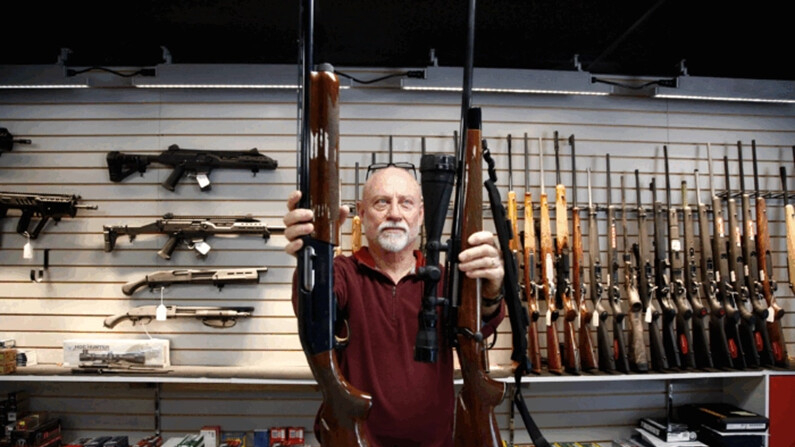 Un hombre muestra un rifle de caza Remington 700 y una escopeta Remington 1100 disponibles para la venta en la armería Atlantic Outdoors en Stokesdale, Carolina del Norte, el 26 de marzo de 2018. (Brian Blanco/Getty Images)
