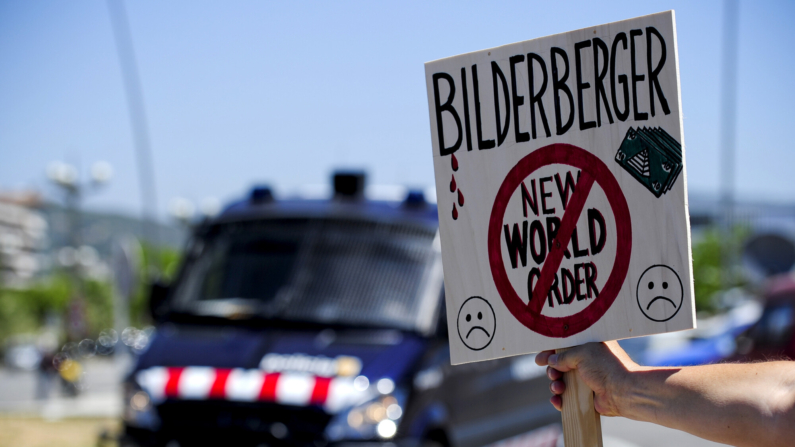 Una pancarta contra la reunión del Grupo Bilderberg delante de un furgón antidisturbios el 3 de junio de 2010 en Sitges, cerca de Barcelona durante la anterior reunión que se celebró en España. AFP PHOTO/ JOSEP LAGO (Photo credit should read JOSEP LAGO/AFP via Getty Images)