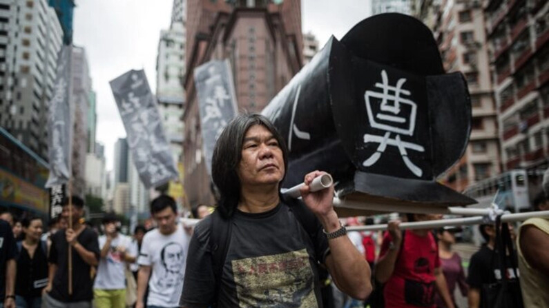 Leung Kwok-hung, conocido como "Pelo Largo", ayuda a sostener un ataúd simbólico mientras asiste a una concentración en Hong Kong el 31 de mayo de 2015, para conmemorar la represión de 1989 en la plaza de Tiananmen de Beijing, antes del 26º aniversario del incidente. (Anthony Wallace/AFP vía Getty Images)