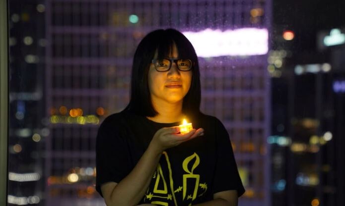 La vicepresidenta de la Alianza de Hong Kong en Apoyo de los Movimientos Patrióticos Democráticos de China, Chow Hang Tung, posa con una vela antes del 32º aniversario de la masacre de manifestantes prodemocráticos en la plaza de Tiananmen de Pekín en 1989, en Hong Kong, el 3 de junio de 2021. (Lam Yik/Reuters)