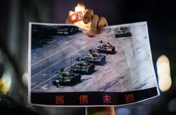 Un hombre sostiene un póster del famoso «Hombre Tanque» que se paró frente a los tanques militares chinos en la Plaza Tiananmen en Beijing el 5 de junio de 1989, durante una commemoración del evento de la Plaza Tiananmen de 1989, en el Parque Victoria en Hong Kong el 4 de junio de 2020. (Anthony Wallace/AFP vía Getty Images)