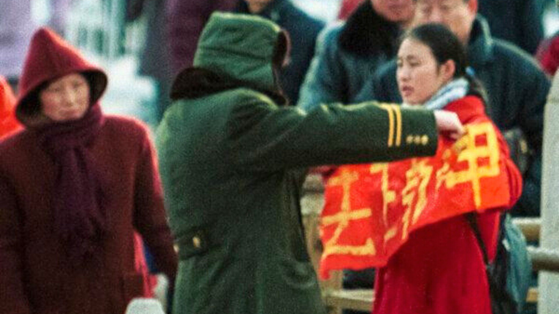 Una mujer que sostiene una pancarta de Falun Gong es detenida por la policía en la Puerta de Tiananmen de Beijing, China.