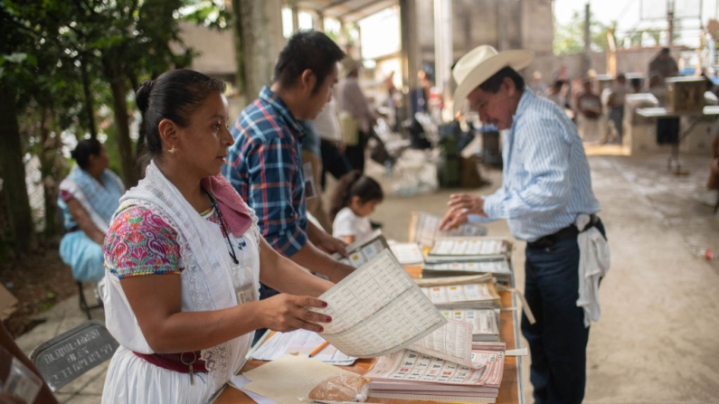 Personas encargadas de organizar el voto revisan documentos para que la gente pueda emitir su voto el 2 de junio de 2024 en Cuetzalan, Puebla, México. (Hector Quintanar/Getty Images)