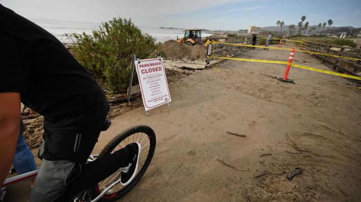 Un niño pasa en bicicleta por delante de un cartel en el que se lee "Playa cerrada"  en Ventura, California, el 29 de diciembre de 2023. (ROBYN BECK/AFP vía Getty Images)