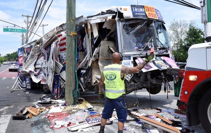 Los restos de un autobús propiedad de una pareja que vendía artículos pro-Donald Trump son remolcados en el distrito neoyorquino de Staten Island, después de que chocara contra varias señales de tráfico y postes de servicios públicos, el 2 de junio de 2024. (Steve White/Staten Island Advance vía AP)