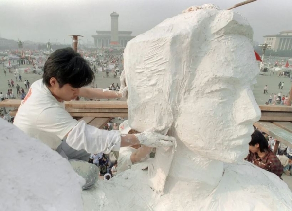 Un estudiante de un instituto de arte enyesa el cuello de la estatua de la «Diosa de la Democracia», una réplica de la Estatua de la Libertad de Nueva York, en la plaza de Tiananmen de Beijing, China, el 30 de mayo de 1989. (Catherine Henriette/AFP/Getty Images)