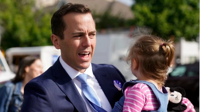 Rob Menendez, hijo del actual senador Bob Menendez, saluda a sus seguidores mientras sostiene a su hija Olivia, de 2 años, tras votar en Jersey City, Nueva Jersey, el 7 de junio de 2022. (Seth Wenig/Foto AP)