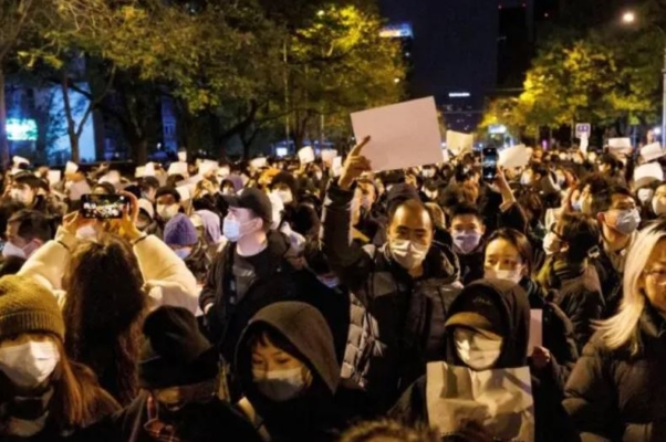 Varias personas sostienen hojas de papel blanco en protesta por las restricciones de la COVID-19, tras una vigilia por las víctimas de un incendio en Urumqi, en Pekín, el 27 de noviembre de 2022. (Thomas Peter/Reuters)