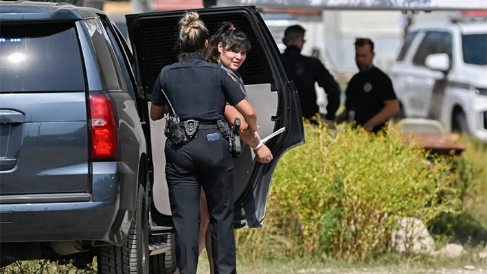 Un ayudante del sheriff del condado de Bexar (izquierda) habla con una mujer esposada durante una operación policial en San Antonio, Texas, el 6 de junio de 2024. (Darren Abate/Foto AP)