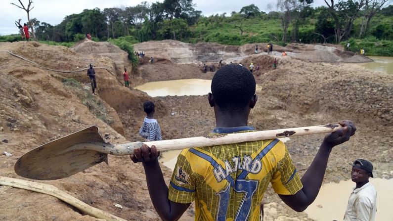 Un hombre sostiene una pala mientras la gente trabaja, el 5 de mayo de 2014, para encontrar polvo de oro en la mina de oro Gam, en Gaga, en el oeste de la República Centroafricana. (Issouf Sanago/AFP vía Getty Images)