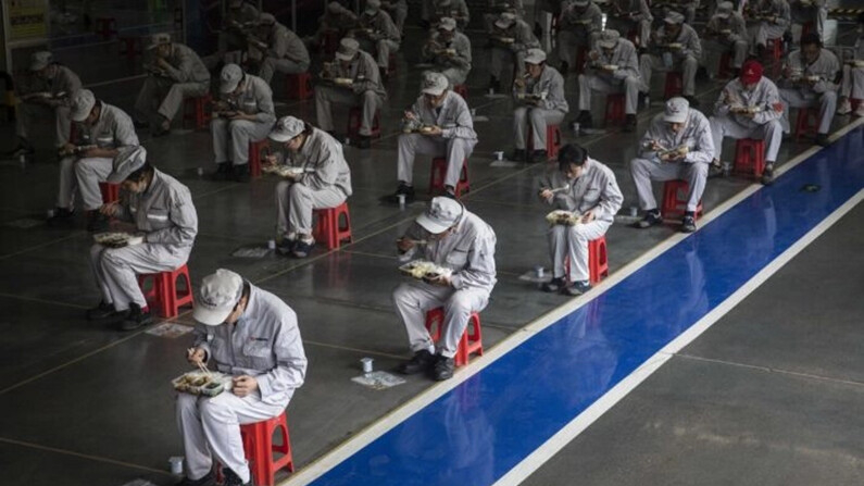 Empleados comen su almuerzo mientras permanecen a 2 metros de distancia unos de otros en la planta de Dongfeng Fengshen, en Wuhan, provincia de Hubei, China, el 24 de marzo de 2020. (Getty Images)