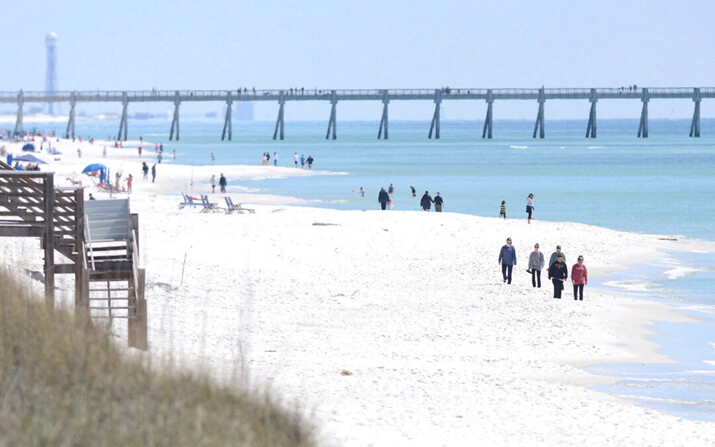 La gente camina a lo largo de la costa en Navarre Beach, Florida, el 27 de marzo de 2013. (Nick Tomecek/Northwest Florida Daily News vía AP)