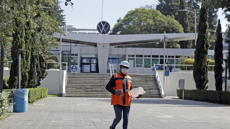 Una persona camina frente a la fachada de la planta armadora Volkswagen, en el estado de Puebla (México). Fotografía de archivo. EFE/Hilda Ríos