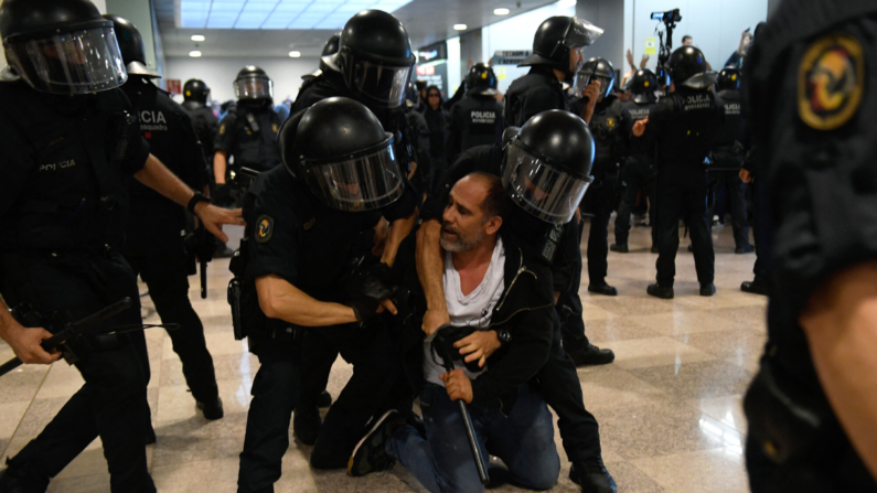 Agentes de la policía regional catalana 'Mossos D'Esquadra' agarran a un manifestante en el aeropuerto de El Prat. (Foto de Josep LAGO / AFP) (Foto de JOSEP LAGO/AFP vía Getty Images)