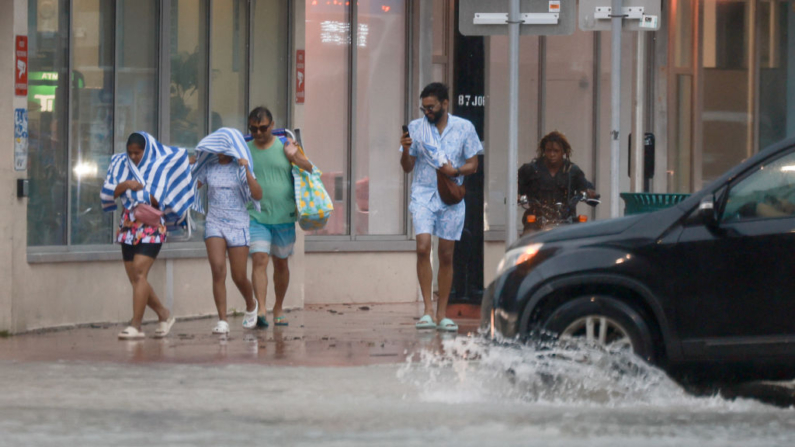 La gente se abre paso a través de la lluvia el 12 de junio de 2024 en Miami Beach, Florida. (Joe Raedle/Getty Images)