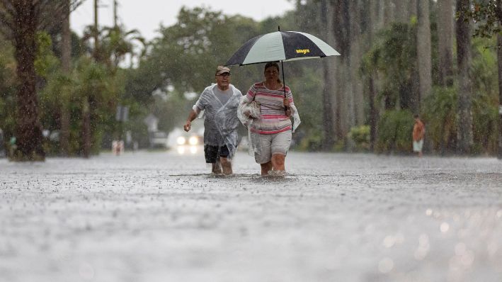 Jim Comunale y Pam Mervos caminan por Arthur Street mientras fuertes lluvias inundan el vecindario el miércoles, 12 de junio de 2024 en Hollywood, Florida (Matias J. Ocner/Miami Herald vía AP)