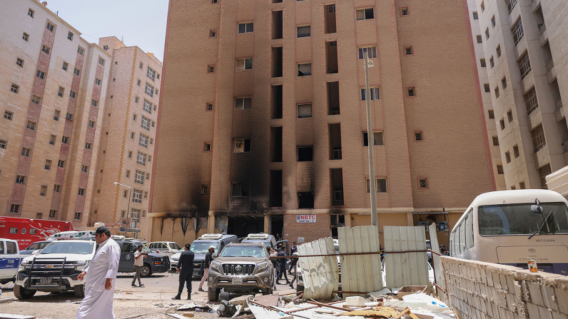 Varias personas pasan por delante de un edificio incendiado en la ciudad de Kuwait el 12 de junio de 2024. (Yasser Al-Zayyat/AFP vía Getty Images)