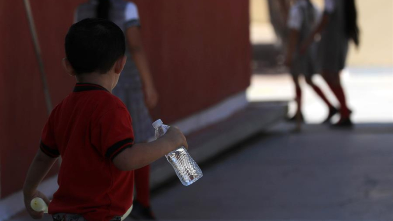 Un estudiante toma agua durante un día con altas temperaturas este jueves 13 de junio de 2024 en Ciudad Juárez (México). EFE/ Luis Torres