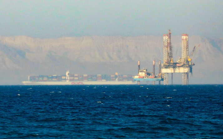 Un portacontenedores cruza una plataforma petrolífera en el Golfo de Suez en dirección al Mar Rojo antes de entrar en el Canal de Suez, a las afueras de El Cairo, Egipto, el 1 de septiembre de 2020. (Amr Abdallah Dalsh/Reuters)