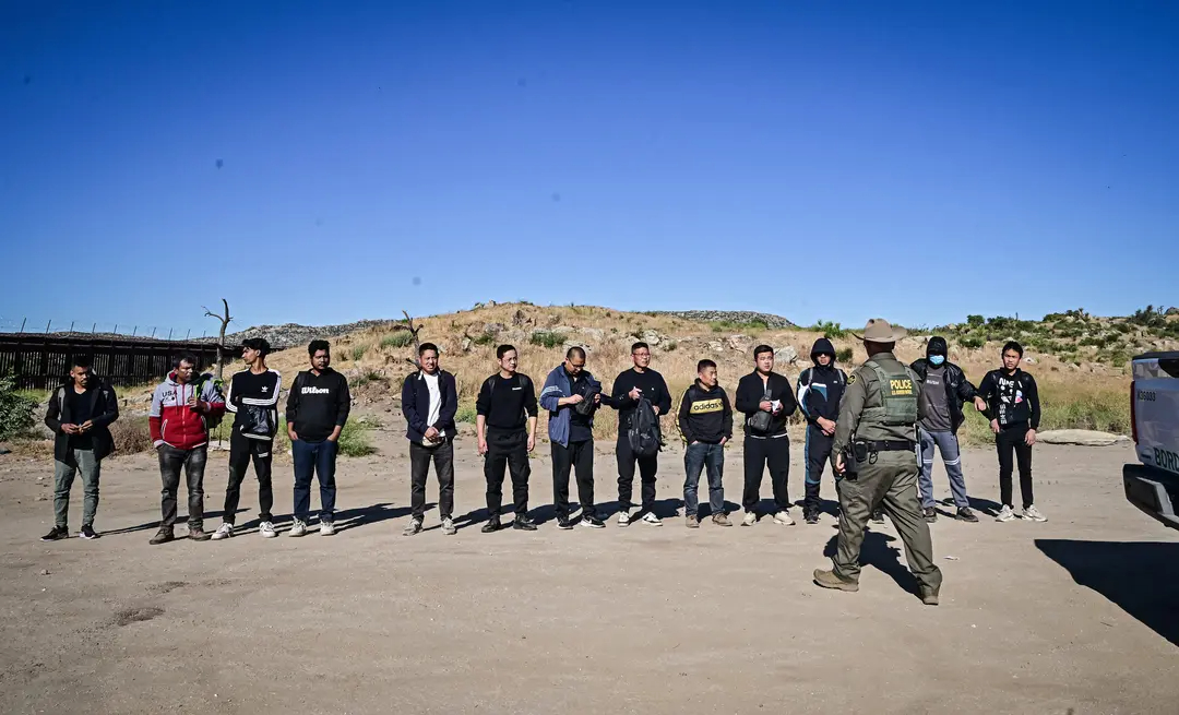 Un agente de la Patrulla Fronteriza detiene a un numeroso grupo de inmigrantes ilegales, en su mayoría chinos, que cruzaron la frontera entre Estados Unidos y México, en Jacumba, California, el 6 de junio de 2024. Desde octubre de 2023, los agentes fronterizos ya han detenido a 48,500 inmigrantes ilegales chinos. (Frederic J. Brown/AFP vía Getty Images)