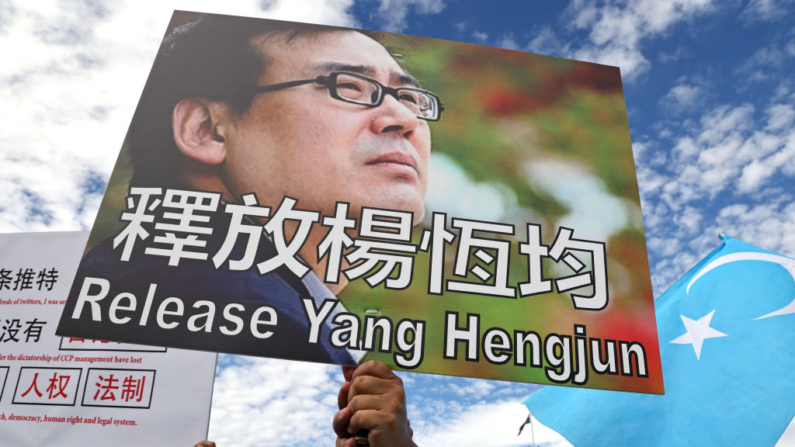 Manifestantes sostienen pancartas exigiendo la liberación del escritor y empresario Yang Hengjun durante una concentración organizada por la Alianza para las Víctimas del Régimen Comunista Chino ante la Casa del Parlamento en Canberra (Australia) el 20 de marzo de 2024. (David Gray/AFP vía Getty Images)