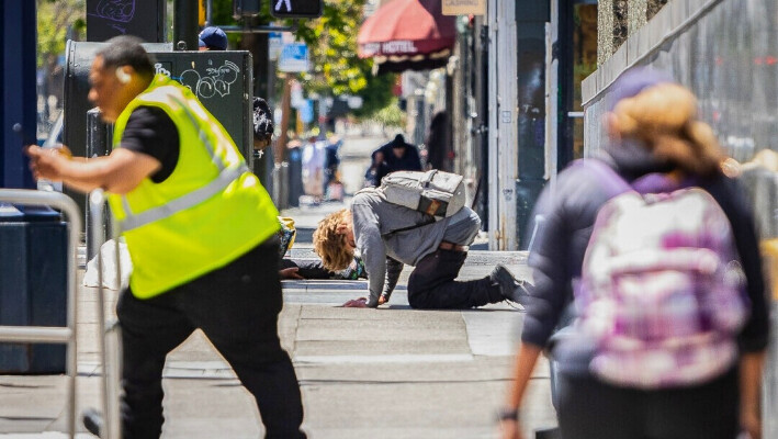 La gente camina alrededor de un consumidor de drogas en el distrito Tenderloin de San Francisco el 16 de mayo de 2024. (John Fredricks/The Epoch Times)