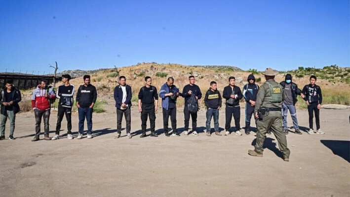 Un agente de la Patrulla Fronteriza detiene a un gran grupo de inmigrantes ilegales, en su mayoría chinos, que cruzaron la frontera entre Estados Unidos y México, en Jacumba, California, el 6 de junio de 2024. (Frederic J. Brown/AFP vía Getty Images)