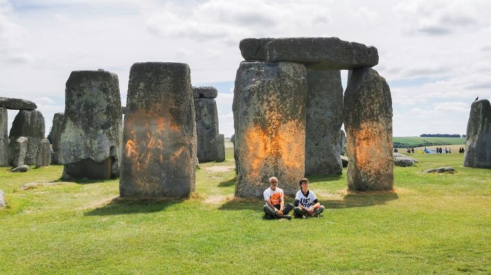 En esta foto distribuida, se ven a los activistas de Just Stop Oil sentados tras rociar una sustancia naranja sobre Stonehenge, en Salisbury, Inglaterra, el miércoles 19 de junio de 2024. (Just Stop Oil vía AP)
