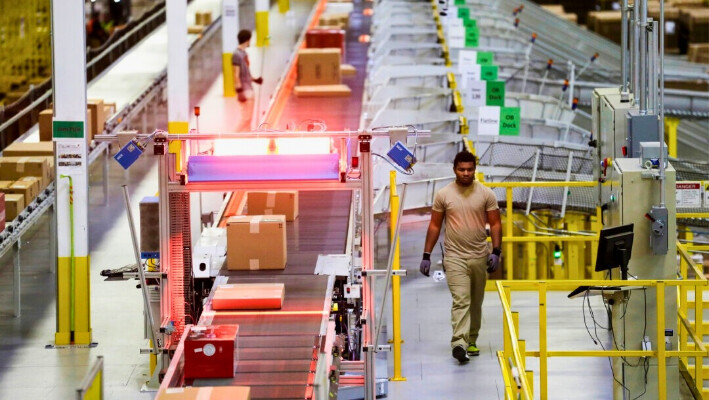 Un trabajador camina cerca de una cinta transportadora de escaneo de alta velocidad en el centro logístico de Amazon en DuPont, Washington, el 30 de noviembre de 2015. (Foto AP/Ted S. Warren)