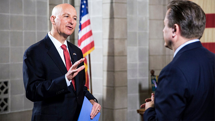 El gobernador de Nebraska, Pete Ricketts (izq.), y Jan Jekielek, presentadora del programa "American Thought Leaders" de The Epoch Times, en el capitolio del estado en Lincoln, Nebraska, el 24 de junio de 2021. (Petr Svab/The Epoch Times)