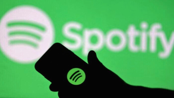 Un teléfono inteligente frente a una proyección en pantalla del logotipo de Spotify tomada el 1 de abril de 2018. (Dado Ruvic/Ilustración/Reuters)