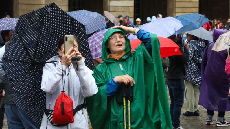 Peregrinos y turistas se resguardan este martes con sus paraguas en la Plaza del Obradoiro durante esta jornada de lluvias originada por una borrasca situada cerca del noroeste peninsular. EFE/Xoán Rey