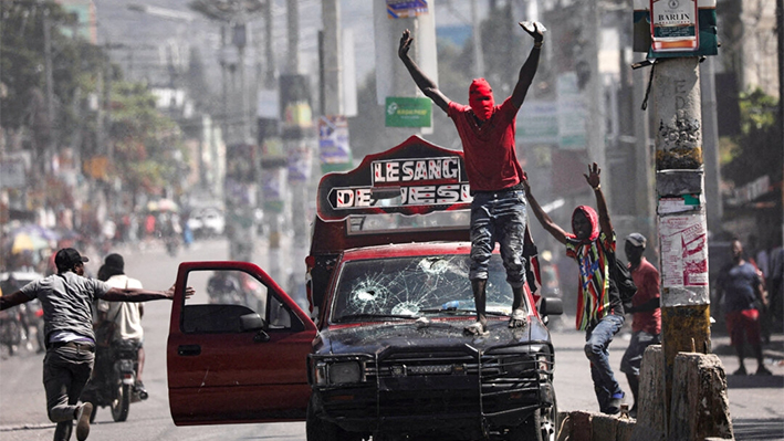 Un hombre con la cara cubierta pide a los manifestantes que se detengan durante una protesta contra el gobierno del primer ministro Ariel Henry en Puerto Príncipe, Haití, el 1 de marzo de 2024. (Ralph Tedy Erol/Reuters)