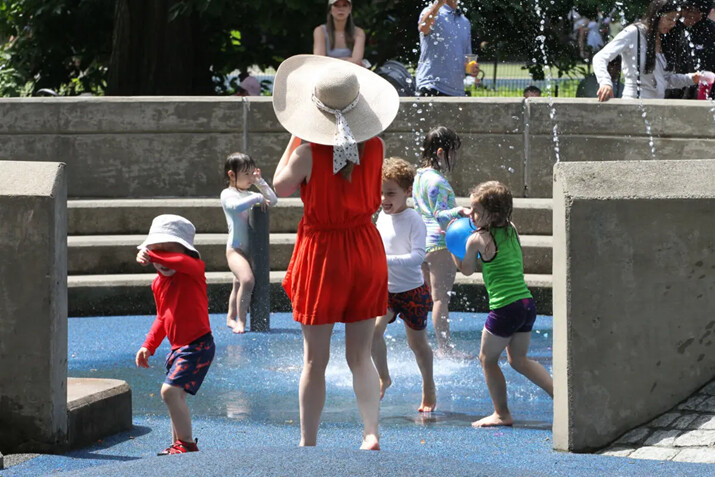 Niños y una dama se refrescan en el parque infantil Heckscher en Central Park, ciudad de Nueva York, el 19 de junio de 2024. (Richard Moore/The Epoch Times)