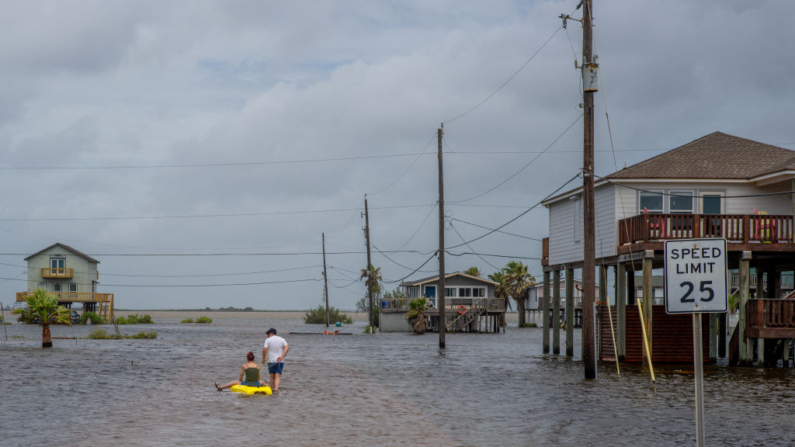 La gente atraviesa el agua de la inundación en un barrio el 20 de junio de 2024 en Surfside Beach, Texas. (Brandon Bell/Getty Images)