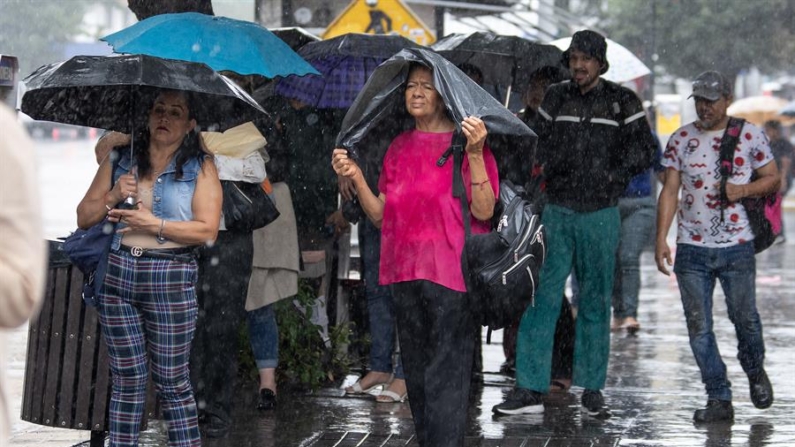 Ciudadanos caminan con paraguas bajo la lluvia en la ciudad de Monterrey (México). EFE/ Miguel Sierra