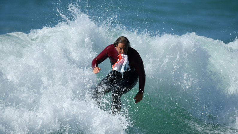 Imagen de archivo de un miembro del público que surfea hacia la orilla para deshacerse de un trozo de plástico de desecho que encontró en el mar. (Foto de Dan Mullan/Getty Images)