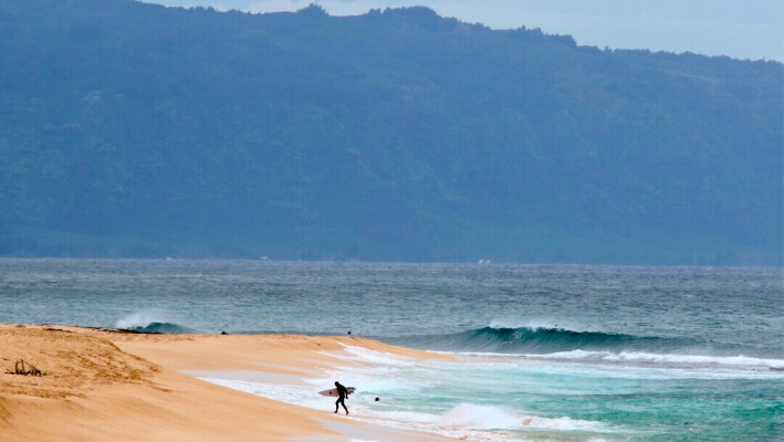 Un surfista sale del océano en la costa norte de Oahu, cerca de Haleiwa, Hawaii, el 31 de marzo de 2020. (Caleb Jones/Foto AP