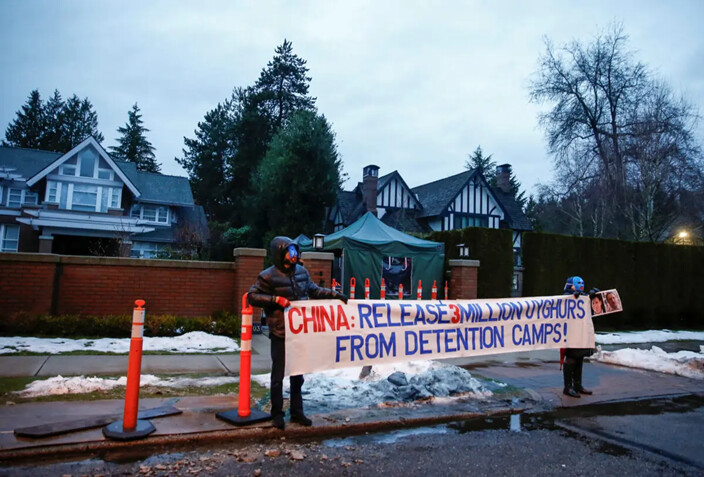 Manifestantes sostienen una pancarta contra los campos uigures de China, etiquetados como centros de formación profesional por el régimen chino, frente a la casa de la CFO de Huawei, Meng Wanzhou, antes de su audiencia de extradición en el Tribunal Supremo de B.C., en Vancouver, Columbia Británica, Canadá, el 20 de enero de 2020. (Lindsey Wasson/Reuters)