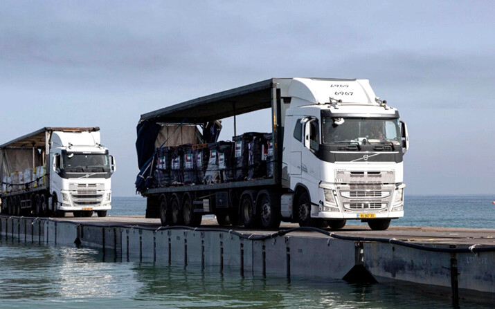 Camiones cargados con ayuda humanitaria de los Emiratos Árabes Unidos y de la Agencia de los Estados Unidos para el Desarrollo Internacional cruzan el muelle Trident antes de llegar a la playa de la Franja de Gaza, el 17 de mayo de 2024. (Sargento Malcolm Cohens-Ashley/Ejército de EE.UU. vía AP)