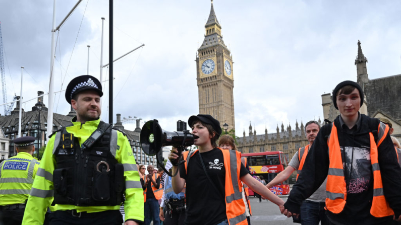 Agentes de policía junto a los activistas climáticos de Just Stop Oil que marchaban lentamente en la plaza del Parlamento de Londres antes de ser detenidos el 19 de julio de 2023. (JUSTIN TALLIS/AFP vía Getty Images)