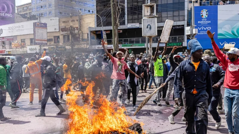 Manifestantes reaccionan junto a neumáticos en llamas durante una protesta contra el proyecto de ley de finanzas en Nairobi, Kenia, el 25 de junio de 2024. (Patrick Meinhardt/Getty Images)