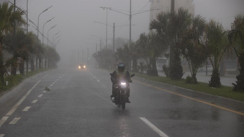 Un motociclista circula bajo una fuerte lluvia debido al paso de una tormenta. Fotografía de archivo. EFE/Orlando Barría