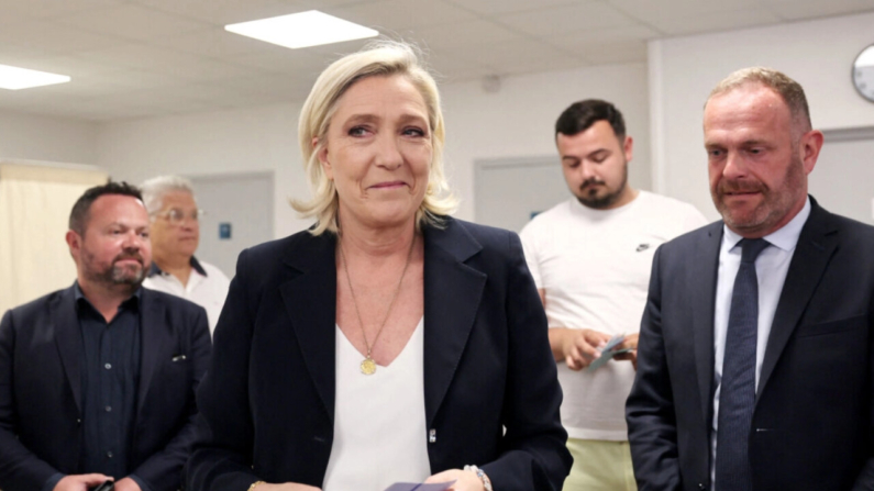 La líder del partido francés Rassemblement National, Marine Le Pen (C), sostiene papeletas junto al alcalde de Henin-Beaumont, Steeve Briois (D), antes de votar en la primera ronda de las elecciones parlamentarias en Henin-Beaumont, al norte de Francia, el 30 de junio de 2024. (François Lo Presti/AFP via Getty Images)