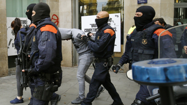 Agentes de la policía autonómica catalana 'Mozos de Escuadra', conducen a sospechosos esposados durante una operación policial contra el consumo y tráfico de drogas en 'narcopisos' el 29 de octubre de 2018, en Barcelona. (Photo credit should read PAU BARRENA/AFP via Getty Images)