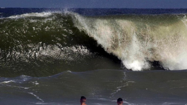 Shaun Clark, (I), y Jim Donnelly observan cómo una gran ola comienza a llegar a la costa en Fernandina Beach, en el condado de Nassau, Florida, el 16 de septiembre de 2003. (Bob Mack/The Florida Times-Union vía AP)