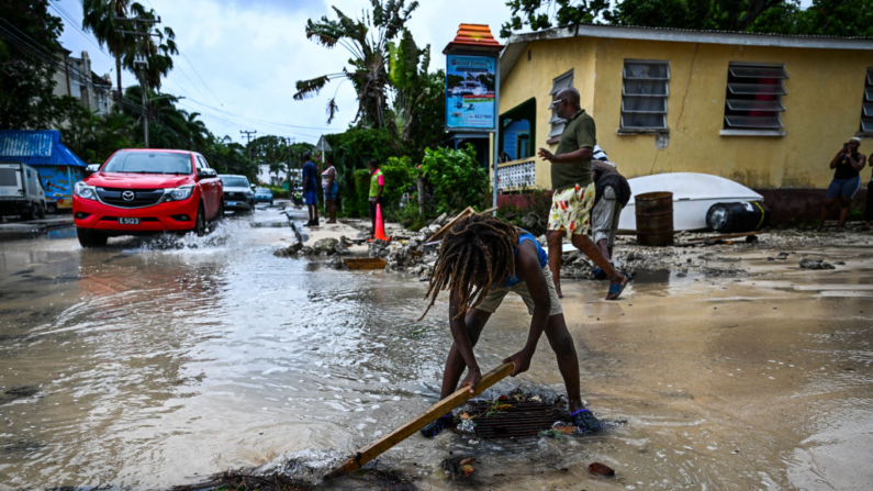 Un niño retira piedras de la calle inundada tras el paso del huracán Beryl en la parroquia de Saint James, Barbados, cerca de Bridgetown, Barbados, el 1 de julio de 2024. (Chandan Khanna/AFP vía Getty Images)