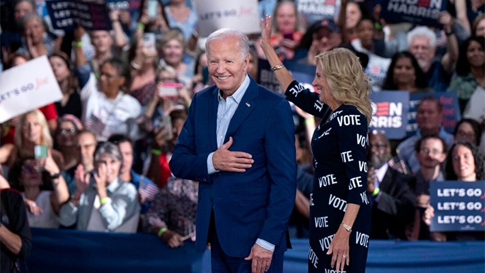 El presidente Joe Biden (izda.) y la primera dama Jill Biden (dcha.), con el lema "VOTA" impreso en su vestido, hacen un gesto a sus seguidores en un acto de campaña posterior al debate en Raleigh, Carolina del Norte, el 28 de junio de 2024. (Allison Joyce/Getty Images)