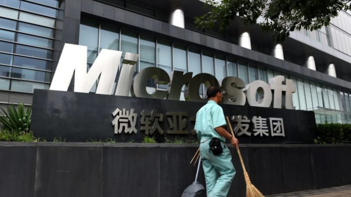 Un limpiador pasa junto a un cartel de Microsoft fuera de un edificio de oficinas de Microsoft en Beijing, el 31 de julio de 2014. (Greg Baker/AFP/Getty Images)