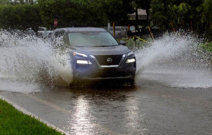 Un coche cruza la carretera inundada por las fuertes lluvias en North Bay Rd en Sunny Isles Beach, Florida, el 11 de junio de 2024. (David Santiago/Miami Herald vía AP)
